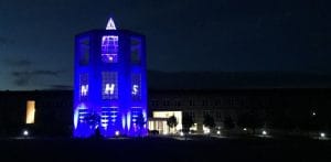 Picture of the Moller Institute Tower illuminated blue for the NHS