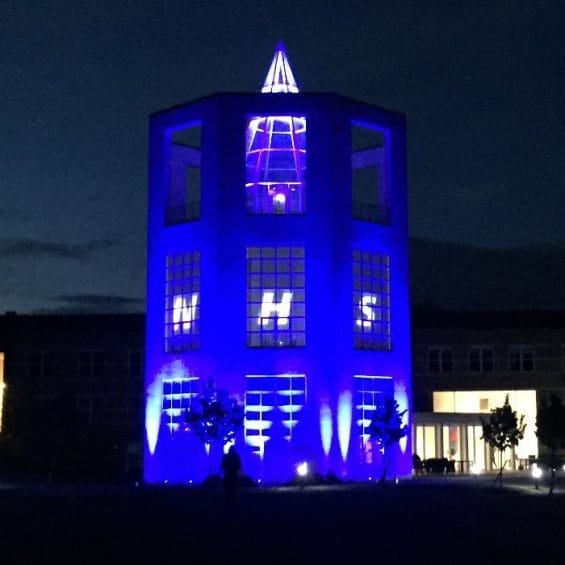 Picture of the Moller Institute tower illuminated blue for the NHS