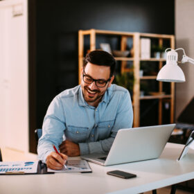 Picture of Young business man working at home with laptop and papers on desk