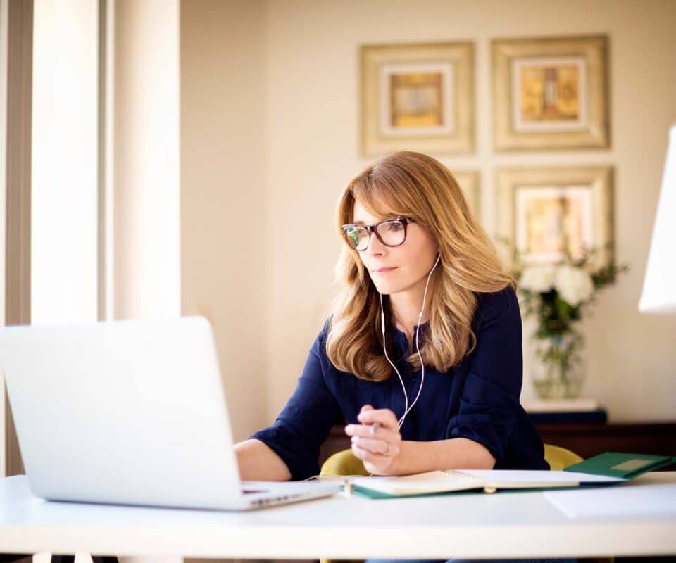 Shot,Of,Middle,Aged,Businesswoman,Using,Earphone,While,Sitting,Behind Picture of women with glasses on laptop
