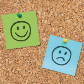 Picture of happy and sad faces on a pin board