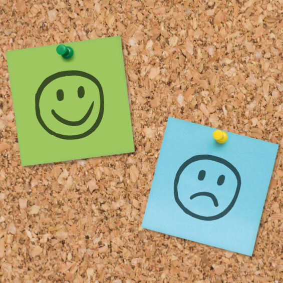 Picture of happy and sad faces on a pin board