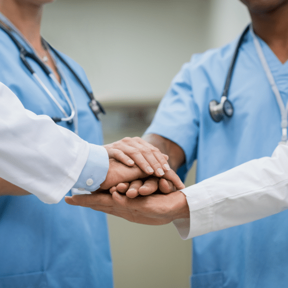 4 doctors of different nationalities and genders stacking hands in a circle